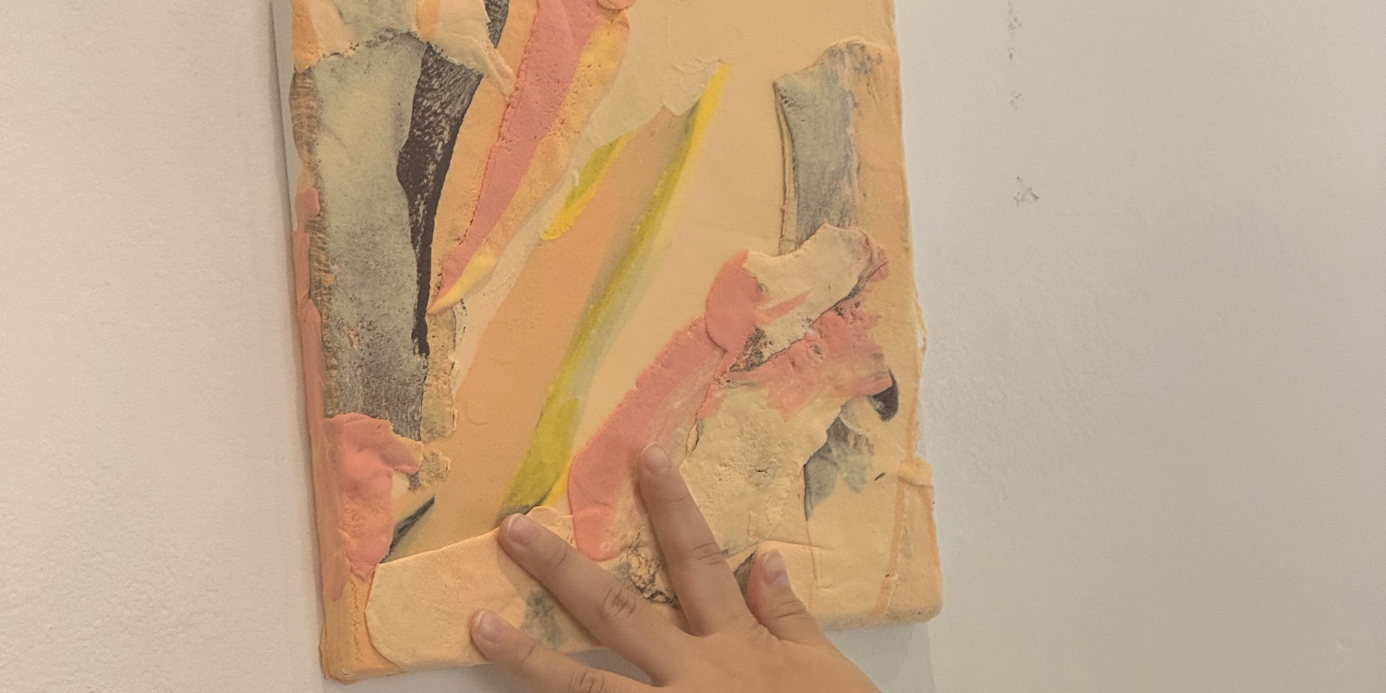 A hand touching a finished canvas on the wall